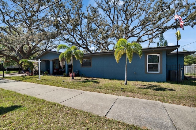 view of front of property with a front lawn, fence, and stucco siding