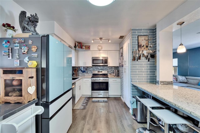 kitchen featuring tasteful backsplash, white cabinets, light wood finished floors, and stainless steel appliances