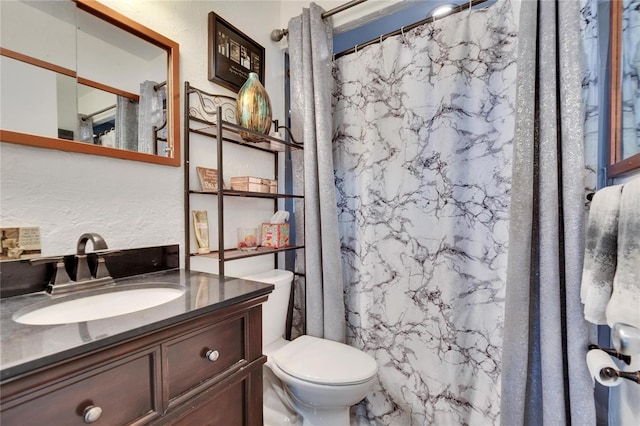 bathroom with curtained shower, toilet, vanity, and a textured wall