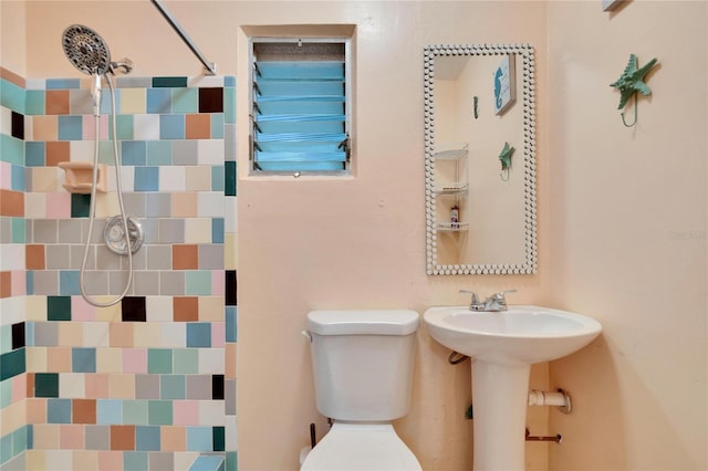 bathroom featuring a tile shower and toilet