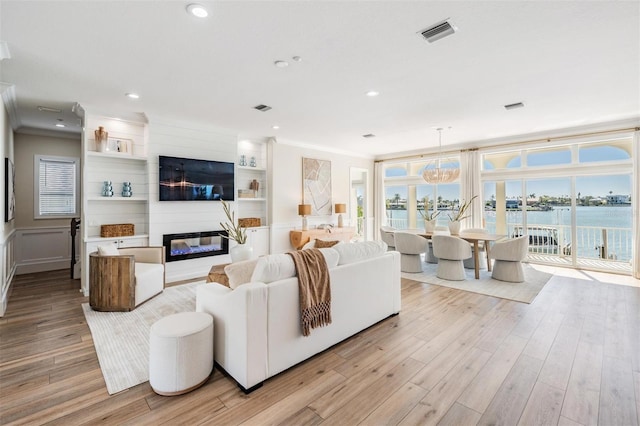 living area with ornamental molding, wood finished floors, and a healthy amount of sunlight