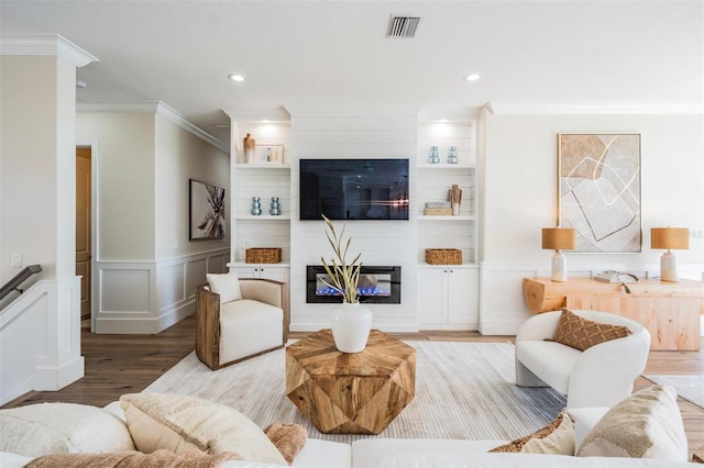 living room with light wood-type flooring, visible vents, a wainscoted wall, and crown molding