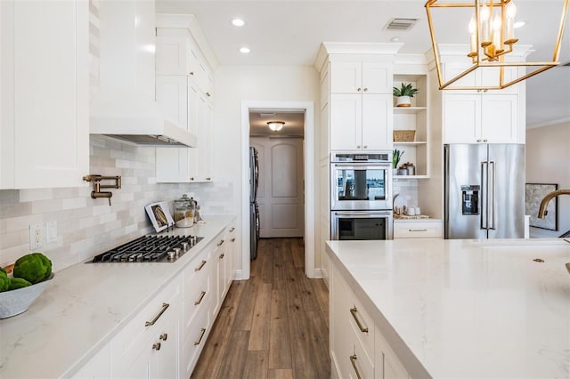 kitchen featuring visible vents, premium range hood, appliances with stainless steel finishes, a notable chandelier, and open shelves