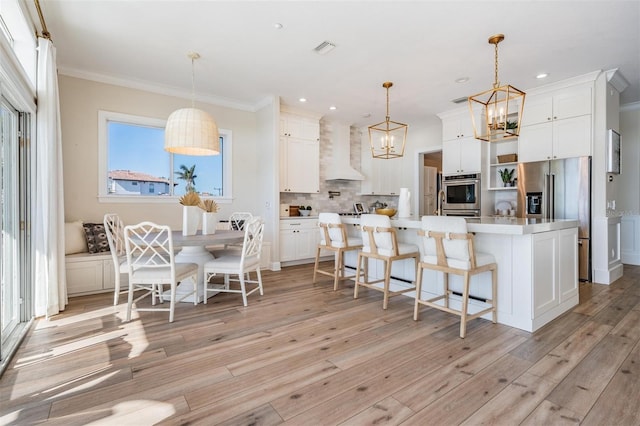 kitchen with visible vents, appliances with stainless steel finishes, wall chimney exhaust hood, an inviting chandelier, and decorative backsplash