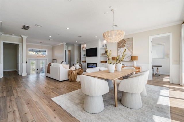 dining room featuring visible vents, light wood-style floors, french doors, a notable chandelier, and a large fireplace