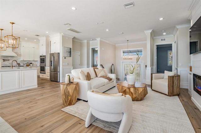 living room with a chandelier, visible vents, and light wood-type flooring