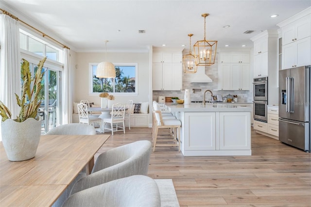 kitchen with decorative backsplash, light countertops, appliances with stainless steel finishes, white cabinetry, and a chandelier