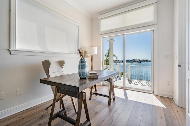 office featuring a water view, baseboards, wood-type flooring, and ornamental molding