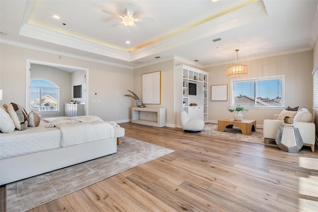 bedroom with a tray ceiling, light wood-style flooring, a notable chandelier, and crown molding