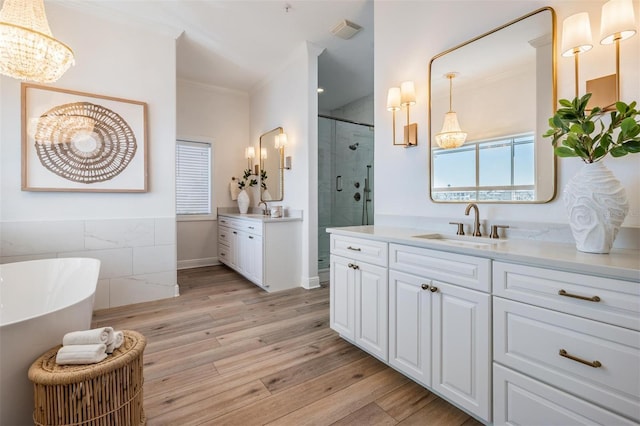 bathroom with ornamental molding, wood finished floors, a stall shower, and a sink