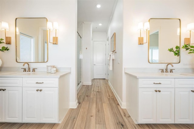 bathroom with a sink, two vanities, wood finished floors, and a shower stall