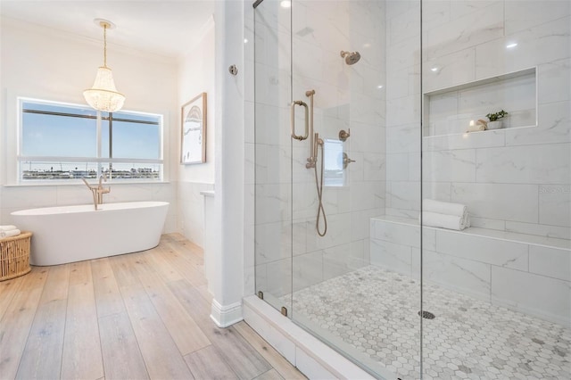 bathroom featuring a shower stall, crown molding, a freestanding bath, wood finished floors, and tile walls