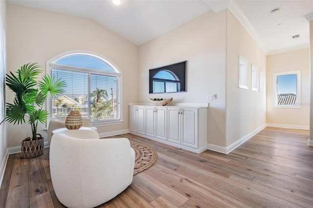 sitting room featuring visible vents, baseboards, light wood-style flooring, and vaulted ceiling