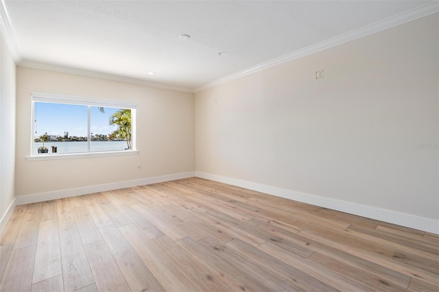 empty room with crown molding, light wood-style flooring, and baseboards