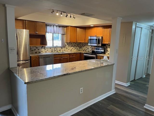 kitchen featuring light stone counters, visible vents, a sink, appliances with stainless steel finishes, and backsplash