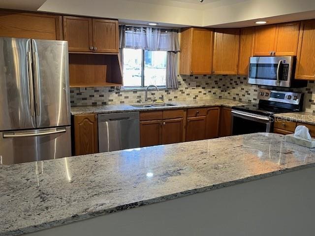 kitchen featuring brown cabinetry, appliances with stainless steel finishes, and a sink