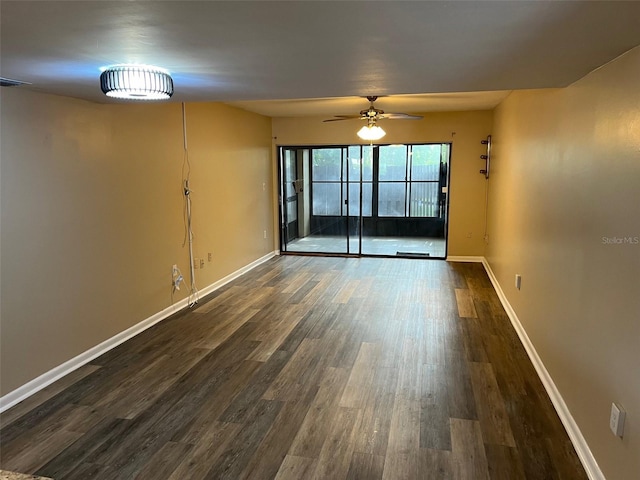 empty room featuring dark wood-style floors, a ceiling fan, and baseboards