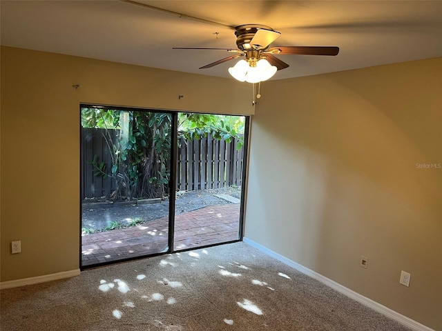 carpeted empty room featuring a ceiling fan and baseboards