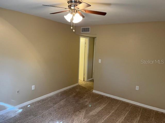 unfurnished room with visible vents, baseboards, carpet, and ceiling fan