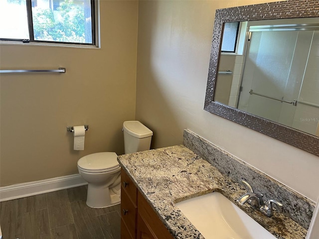 full bath with an enclosed shower, toilet, wood finished floors, baseboards, and vanity