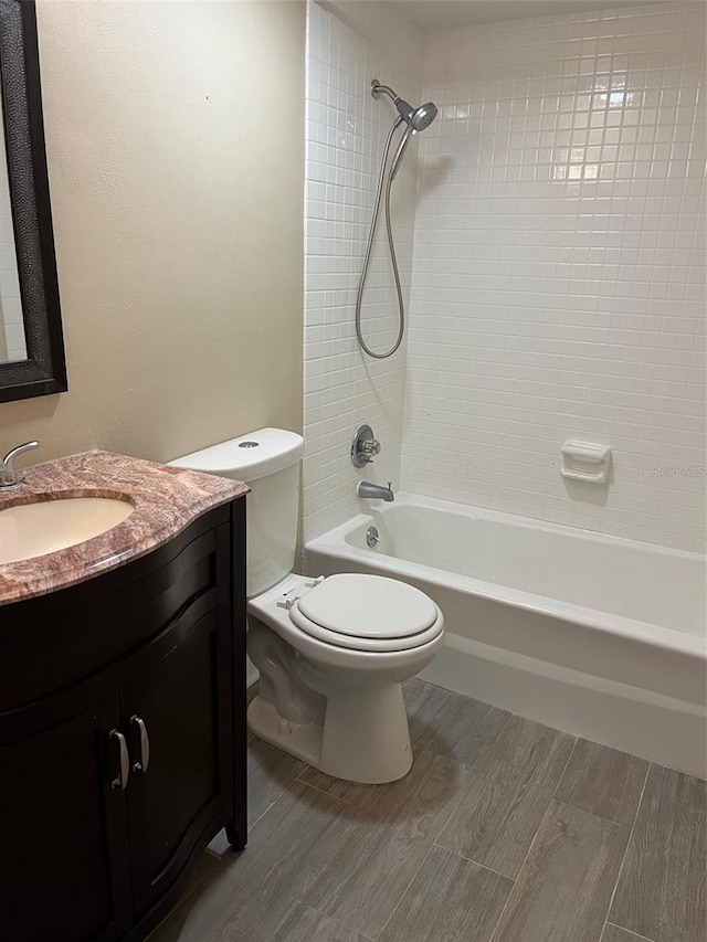 bathroom with toilet, vanity,  shower combination, and wood finished floors