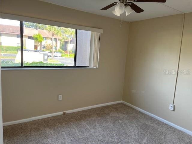 empty room with carpet flooring, baseboards, and ceiling fan