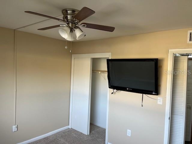 unfurnished bedroom featuring a ceiling fan, baseboards, visible vents, a closet, and carpet flooring