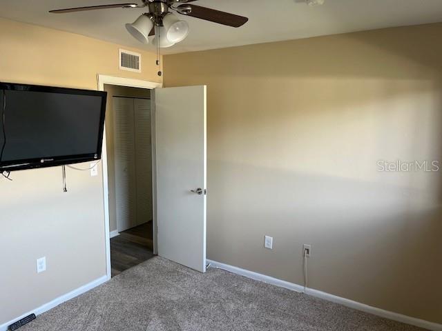 unfurnished bedroom featuring visible vents, baseboards, carpet, and a ceiling fan