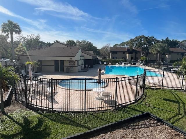 community pool with a patio area and fence