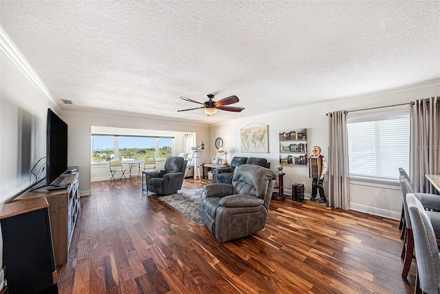 living area with visible vents, dark wood-type flooring, ceiling fan, baseboards, and ornamental molding