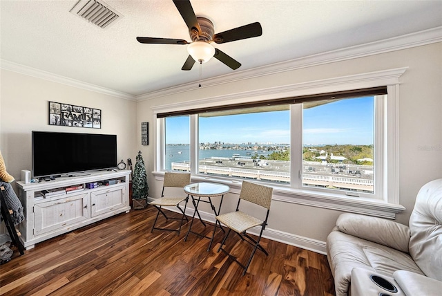 sitting room with visible vents, dark wood-type flooring, baseboards, ornamental molding, and a ceiling fan