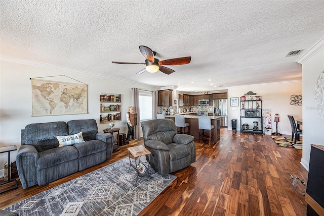 living area with visible vents, ornamental molding, a textured ceiling, dark wood-style floors, and ceiling fan