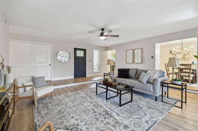 living area featuring visible vents, baseboards, wood finished floors, and ceiling fan with notable chandelier