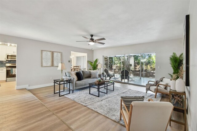 living room with baseboards, light wood-type flooring, and ceiling fan