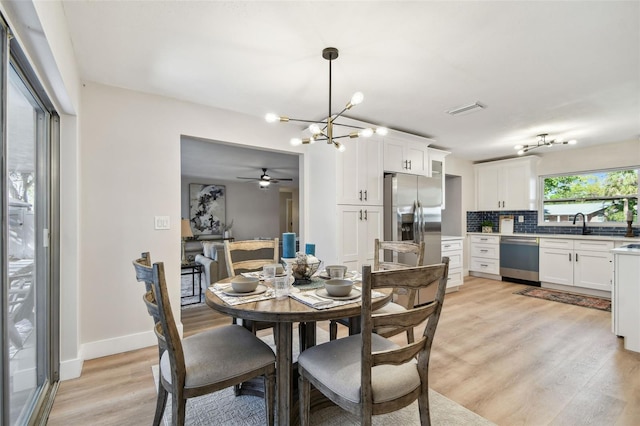 dining space with a notable chandelier, baseboards, visible vents, and light wood finished floors