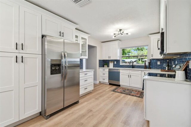 kitchen featuring backsplash, white cabinets, stainless steel appliances, and light countertops