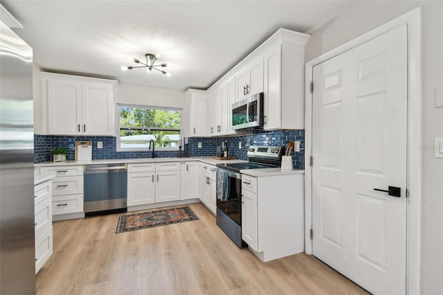 kitchen with light wood finished floors, tasteful backsplash, appliances with stainless steel finishes, and a sink