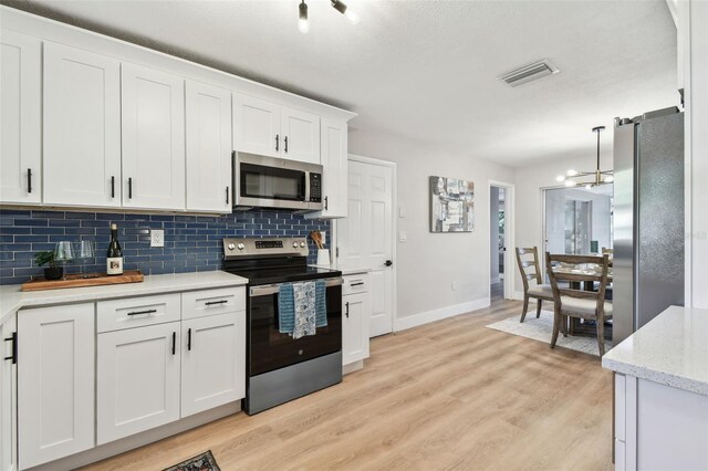 kitchen featuring tasteful backsplash, light wood-style floors, visible vents, and stainless steel appliances