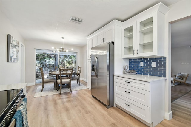 kitchen with light wood-type flooring, visible vents, white cabinetry, stainless steel fridge with ice dispenser, and light countertops