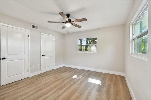 unfurnished bedroom featuring a ceiling fan, wood finished floors, visible vents, and baseboards