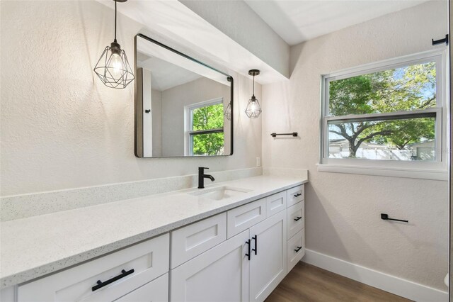 bathroom featuring vanity, wood finished floors, baseboards, and a textured wall