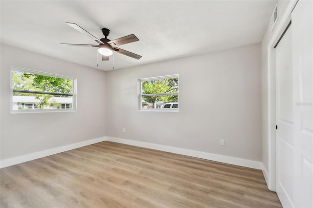 unfurnished bedroom featuring a closet, multiple windows, light wood-type flooring, and baseboards