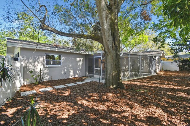 back of property featuring stucco siding, fence, and a sunroom