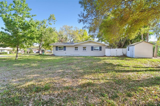 back of house featuring an outdoor structure, a storage shed, a yard, and fence