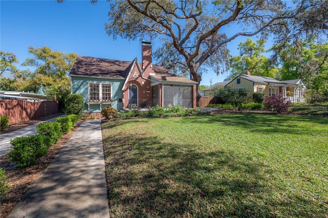 view of front facade with a front yard, fence, brick siding, and a chimney