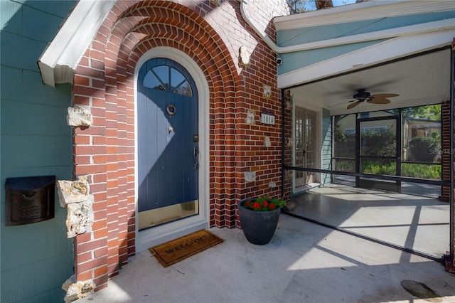 view of exterior entry featuring brick siding and ceiling fan