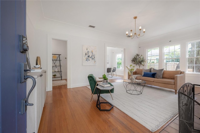 living area with a notable chandelier, wood finished floors, visible vents, and baseboards