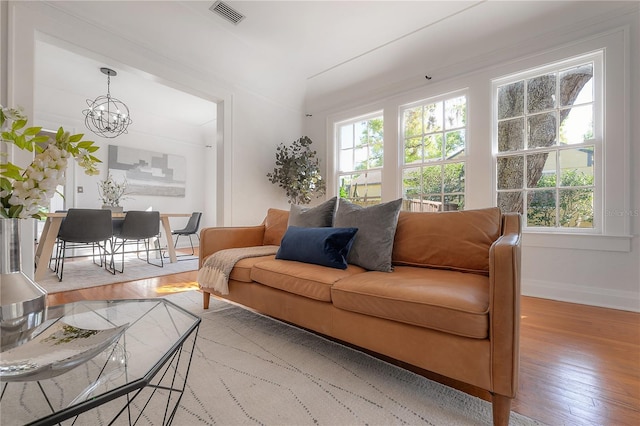 living room featuring a notable chandelier, visible vents, light wood-style flooring, and baseboards