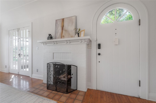 foyer entrance with a brick fireplace, plenty of natural light, and wood finished floors