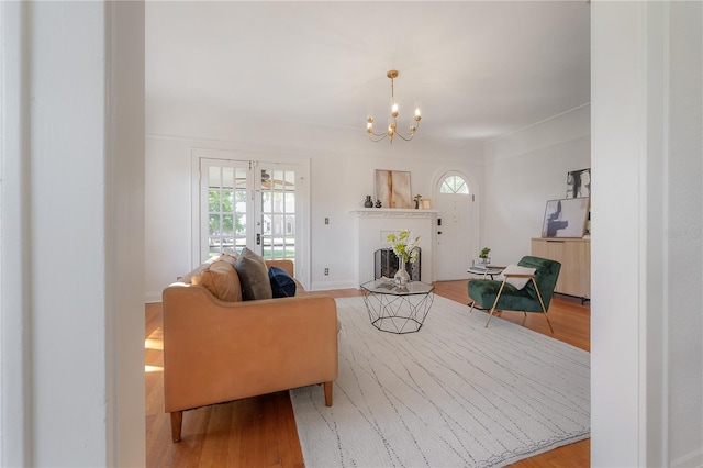 living room with a fireplace, an inviting chandelier, and wood finished floors